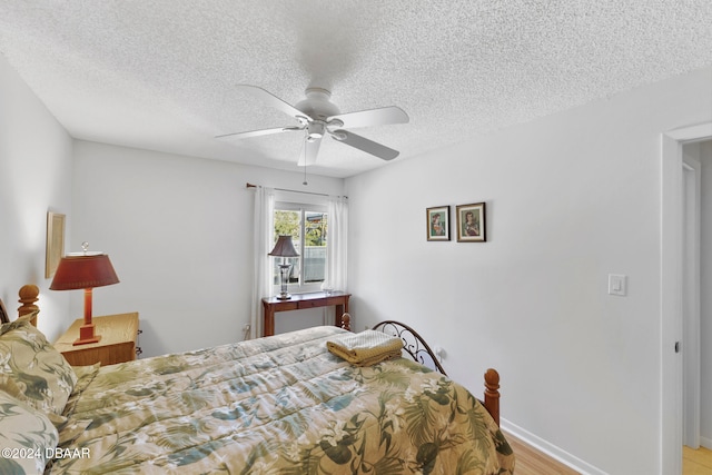 bedroom with a textured ceiling, light hardwood / wood-style floors, and ceiling fan