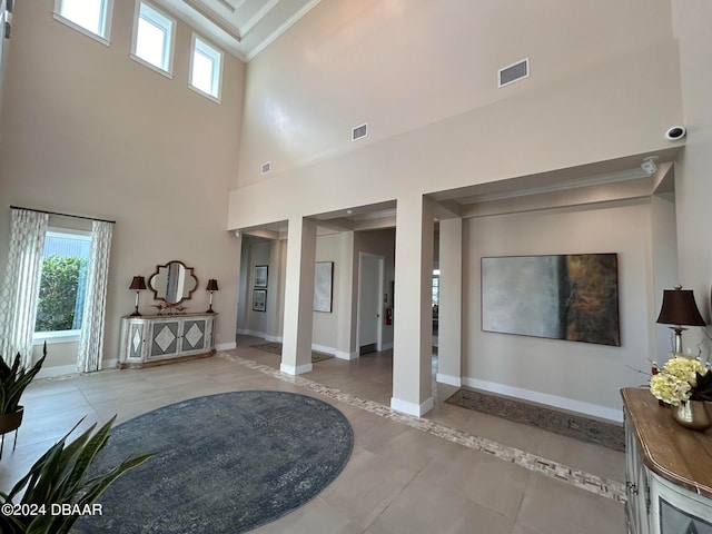 entrance foyer featuring a wealth of natural light, crown molding, and a towering ceiling