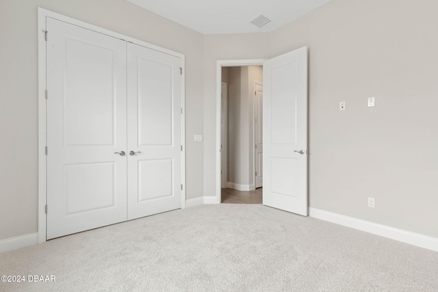 unfurnished bedroom featuring light carpet and a closet