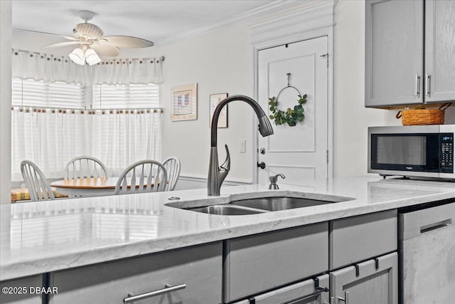 kitchen with appliances with stainless steel finishes, gray cabinets, ornamental molding, and sink