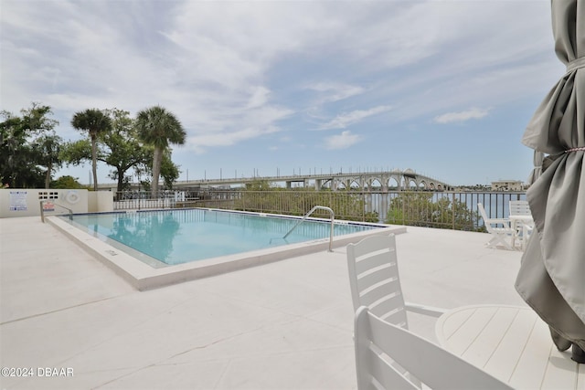 view of pool featuring a water view and a patio area