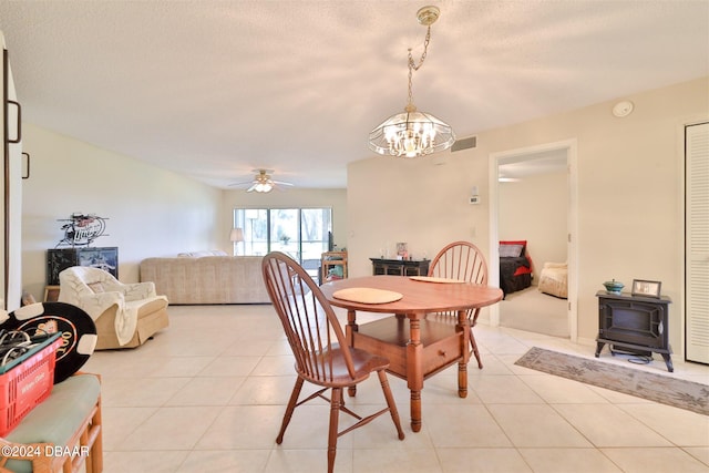 tiled dining space featuring ceiling fan with notable chandelier and a textured ceiling