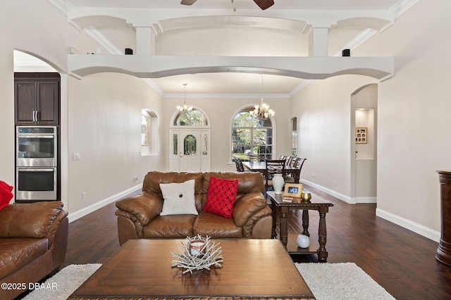 living room featuring dark wood-type flooring, arched walkways, baseboards, and a ceiling fan