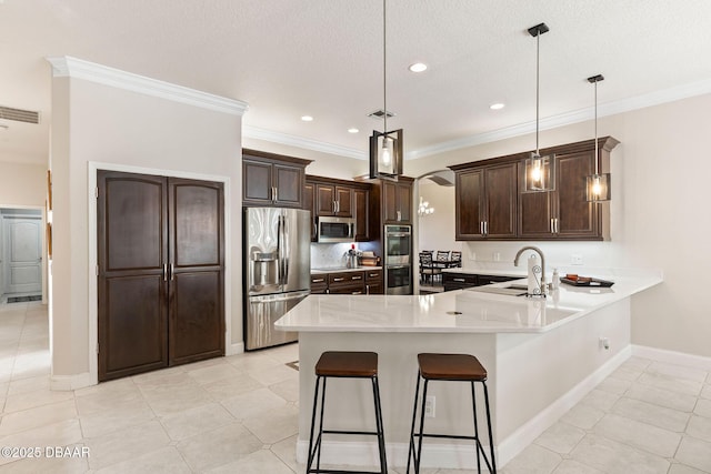 kitchen with light countertops, stainless steel appliances, dark brown cabinets, and a peninsula