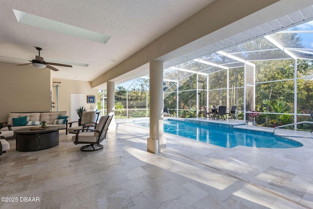 pool featuring an outdoor hangout area, glass enclosure, ceiling fan, and a patio area