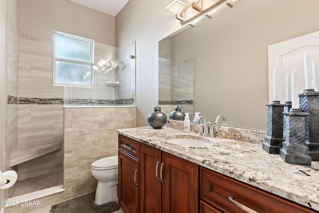 bathroom with vanity, walk in shower, toilet, and tile walls