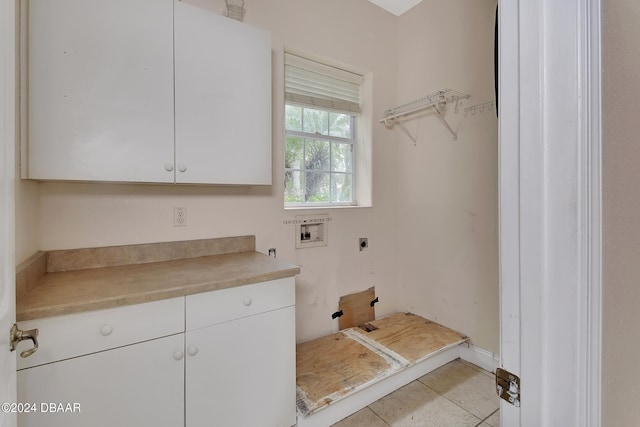 laundry area with electric dryer hookup, hookup for a washing machine, light tile patterned flooring, and cabinets