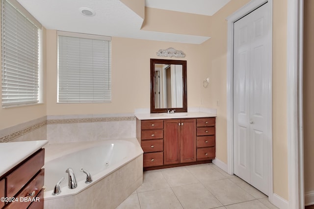 bathroom with tile patterned flooring, vanity, and tiled bath