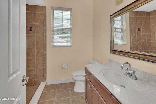 bathroom featuring tile patterned flooring, a tile shower, vanity, and toilet