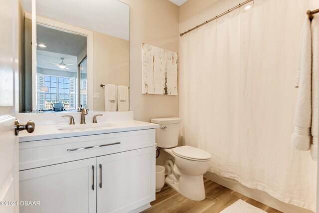 bathroom with hardwood / wood-style floors, ceiling fan, vanity, and toilet