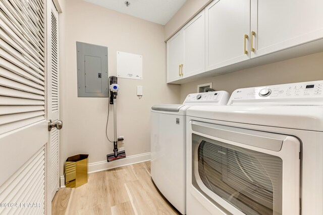 laundry room with electric panel, cabinets, washing machine and clothes dryer, and light hardwood / wood-style floors