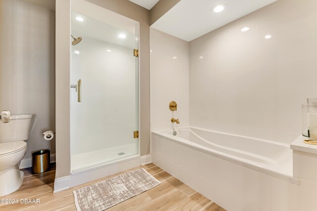 bathroom featuring toilet, shower with separate bathtub, and hardwood / wood-style floors