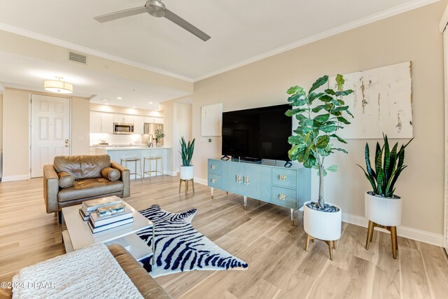 living room featuring ceiling fan, crown molding, and light hardwood / wood-style flooring