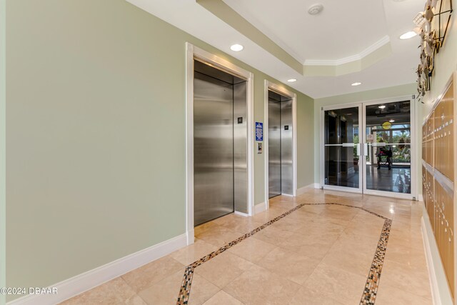 hall with light tile patterned flooring, elevator, a raised ceiling, and crown molding