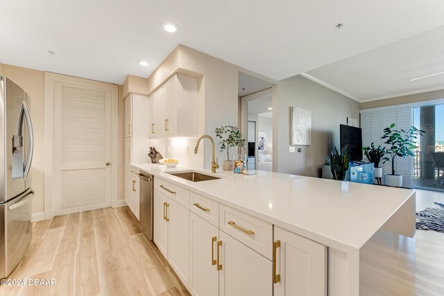 kitchen featuring white cabinets, kitchen peninsula, light hardwood / wood-style flooring, sink, and appliances with stainless steel finishes