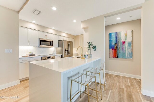 kitchen with stainless steel appliances, light hardwood / wood-style floors, white cabinets, and sink