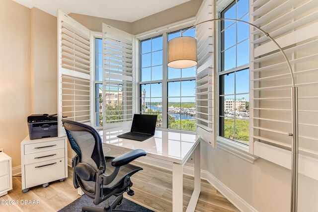 home office featuring plenty of natural light, a water view, and light hardwood / wood-style floors