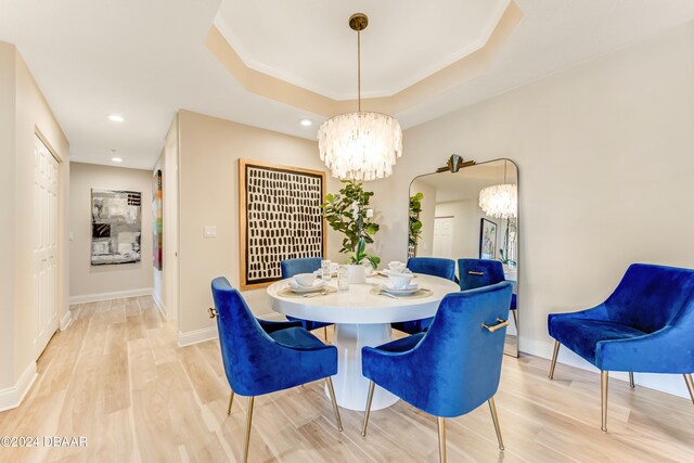 dining area featuring an inviting chandelier, a tray ceiling, and wood-type flooring