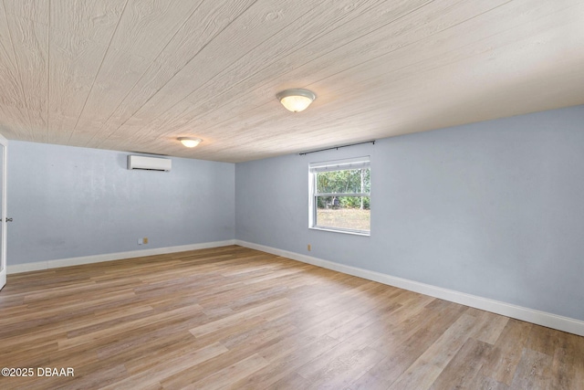 empty room featuring an AC wall unit, light wood finished floors, and baseboards