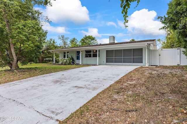 ranch-style home featuring a gate, concrete driveway, and a chimney