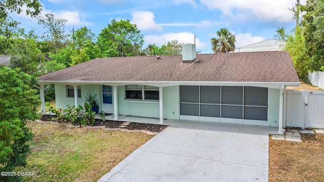 ranch-style home featuring driveway, fence, a chimney, roof with shingles, and stucco siding