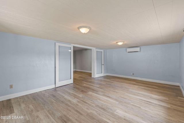 finished basement featuring a wall mounted air conditioner, light wood-style flooring, and baseboards