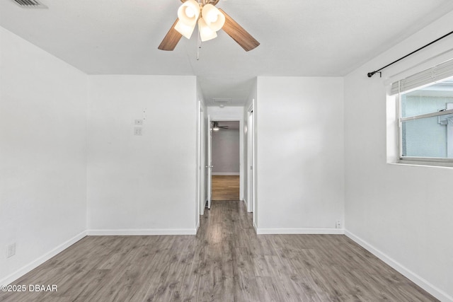 spare room featuring a ceiling fan, wood finished floors, and baseboards