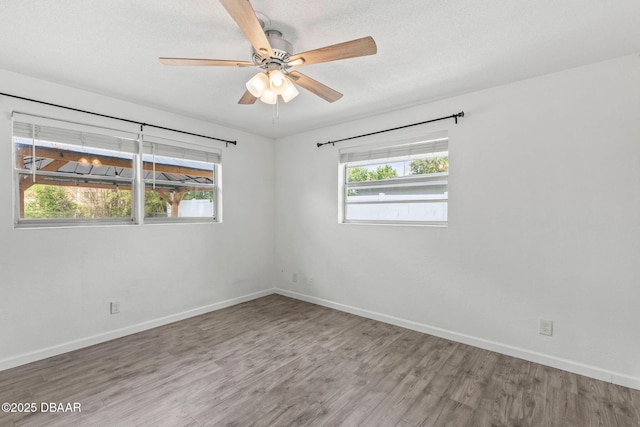 unfurnished room with wood finished floors, baseboards, and ceiling fan