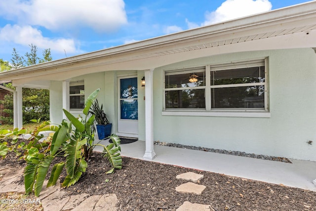 property entrance featuring covered porch and stucco siding