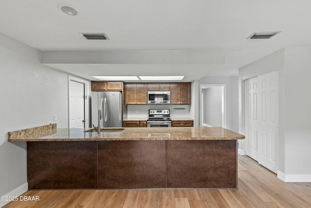 kitchen with stainless steel appliances, baseboards, and light wood finished floors
