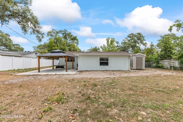 rear view of property with a gazebo, a patio, a storage unit, and a fenced backyard
