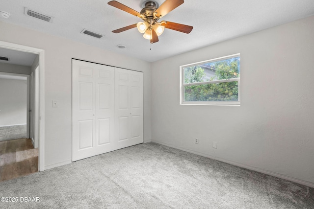 unfurnished bedroom featuring carpet flooring, a closet, baseboards, and ceiling fan