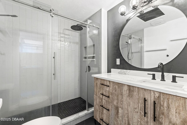 bathroom featuring toilet, a stall shower, and vanity