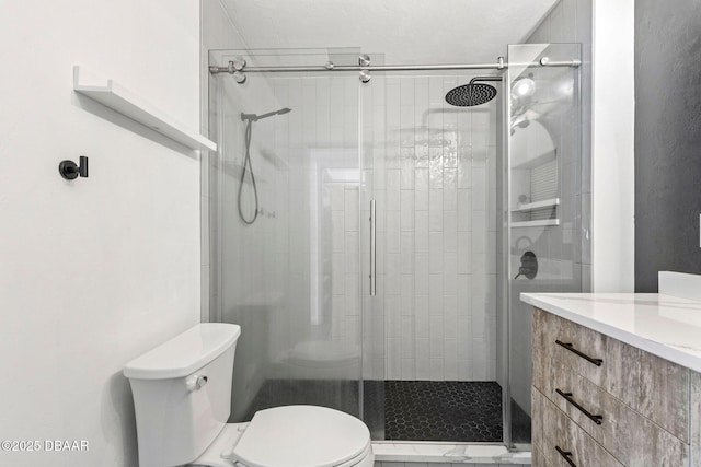bathroom featuring toilet, a stall shower, and vanity