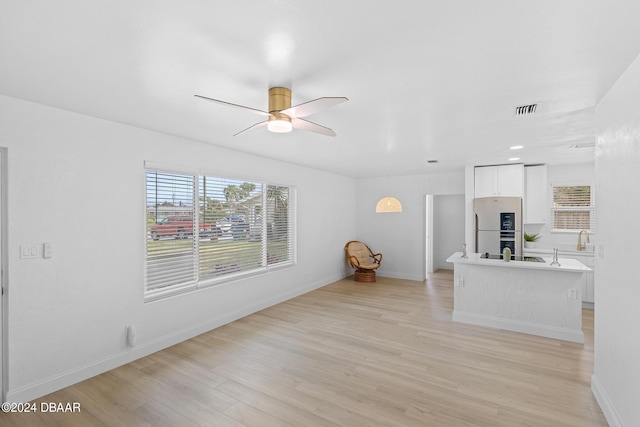 unfurnished living room featuring light wood-type flooring, ceiling fan, and sink