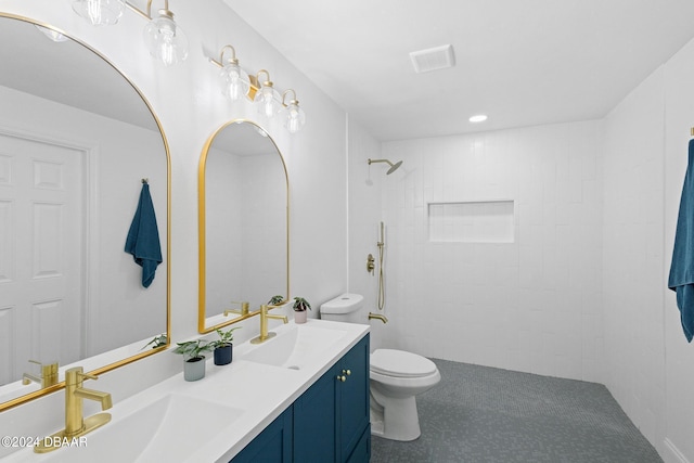 bathroom with tiled shower, vanity, and toilet