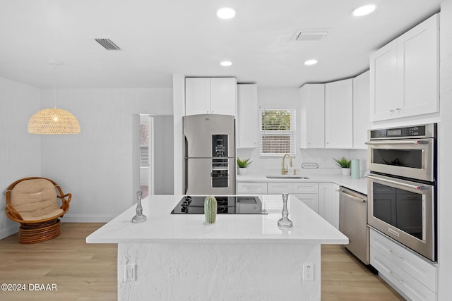 kitchen with sink, white cabinetry, stainless steel appliances, and hanging light fixtures