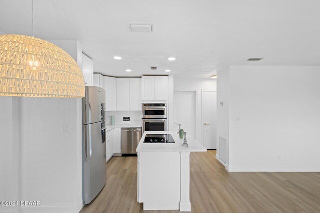 kitchen featuring a center island, white cabinets, light hardwood / wood-style flooring, and appliances with stainless steel finishes