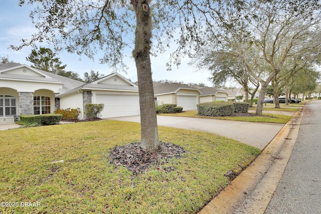 ranch-style home with a front yard, stone siding, driveway, and an attached garage