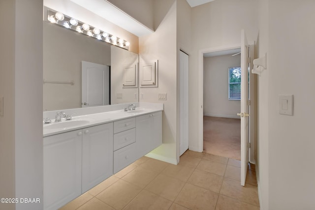 bathroom featuring double vanity, tile patterned flooring, a sink, and baseboards