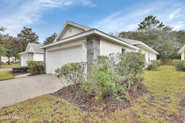 view of property exterior featuring an attached garage, stucco siding, driveway, and a yard