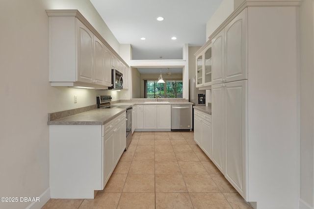 kitchen with light tile patterned floors, recessed lighting, appliances with stainless steel finishes, glass insert cabinets, and white cabinets