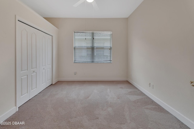 unfurnished bedroom featuring carpet floors, a closet, baseboards, and a ceiling fan