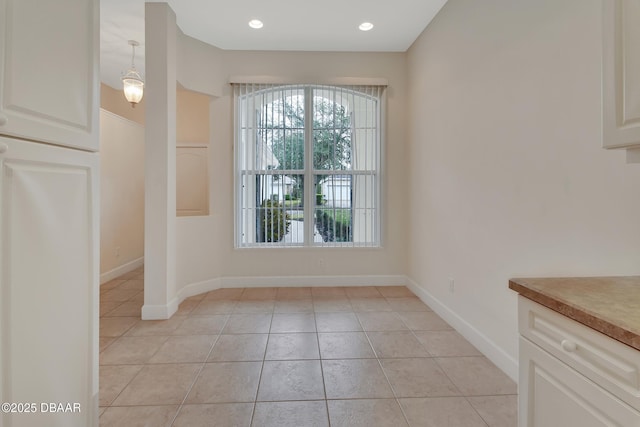 unfurnished dining area with light tile patterned floors, baseboards, and recessed lighting