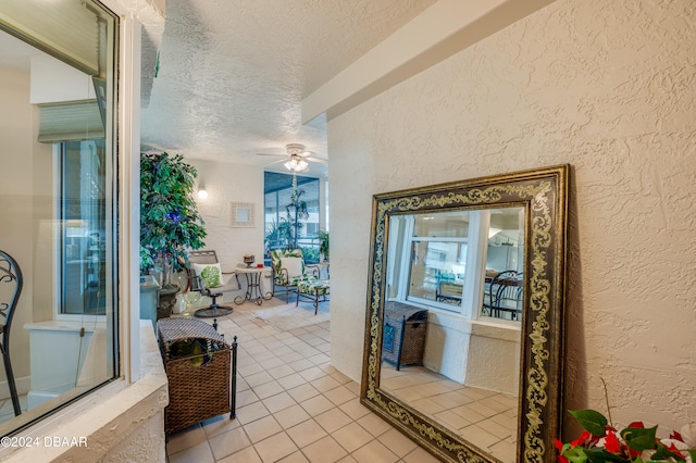 hallway with a textured ceiling and light tile patterned flooring