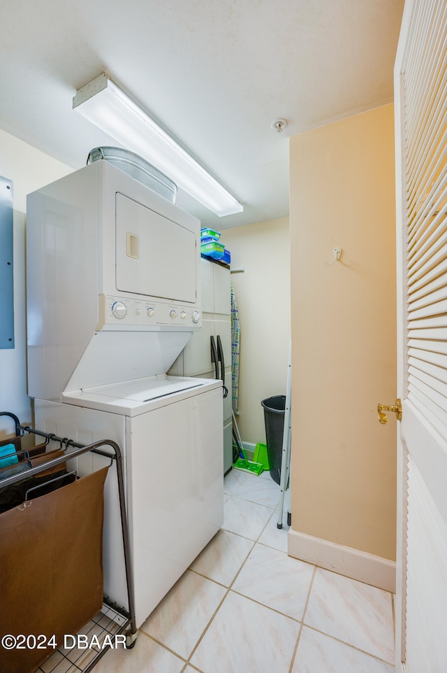 washroom with stacked washing maching and dryer, electric panel, and light tile patterned flooring