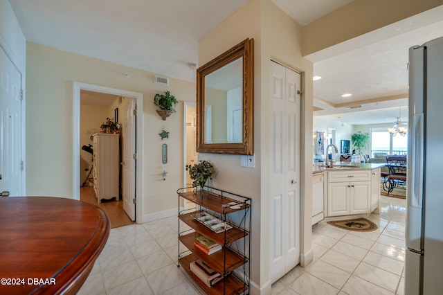 hallway featuring light tile patterned flooring, sink, and a notable chandelier