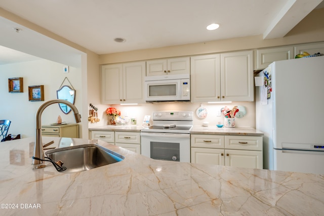 kitchen featuring white appliances, sink, and light stone counters