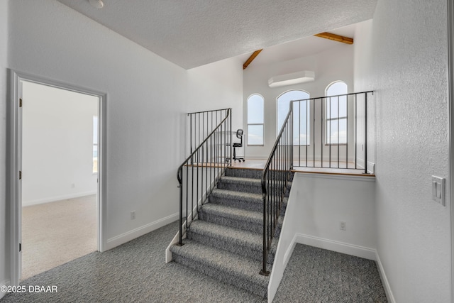 4690 S Atlantic Ave, Ponce Inlet, FL 32127 - staircase featuring carpet flooring, healthy amount of natural light, a wall unit AC, a textured ceiling, and vaulted ceiling