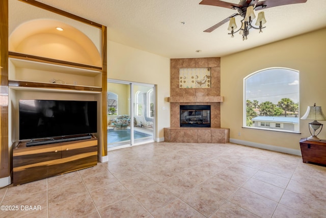 4690 S Atlantic Ave, Ponce Inlet, FL 32127 - unfurnished living room featuring a ceiling fan, tile patterned floors, a tiled fireplace, and a textured ceiling